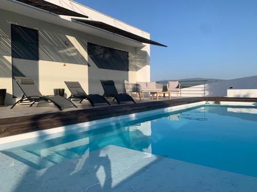 a swimming pool with chairs and a house at Casa com Alma in Bombarral