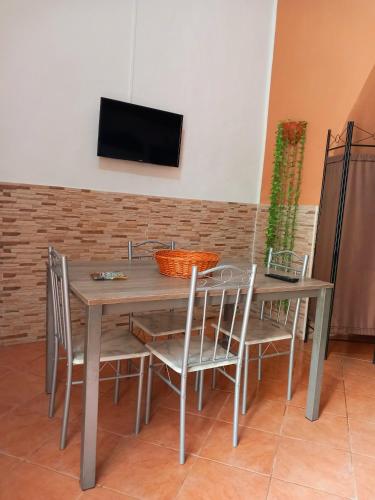 a wooden table with chairs and a television on a wall at La Locanda in Marsala