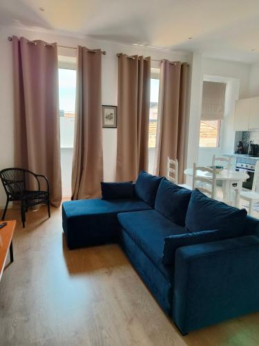 a blue couch in a living room with curtains at Casa Irene in Aveiro
