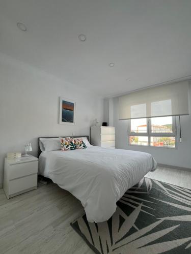 a white bedroom with a large bed and a window at Apartamento en Somo cerca de la playa totalmente equipado - Somocubas in Somo