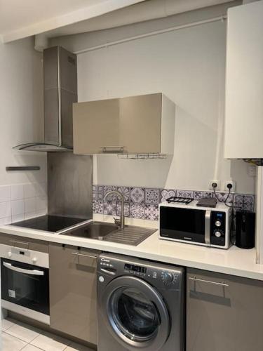 une cuisine avec un lave-linge et un micro-ondes dans l'établissement Charmant Appartement au Moulin Rouge, à Paris