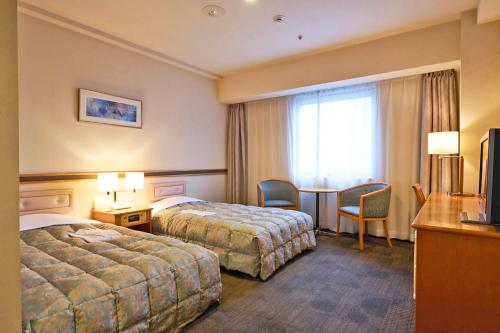 a hotel room with two beds and a desk and a table at Ageo Tobu Hotel in Ageo