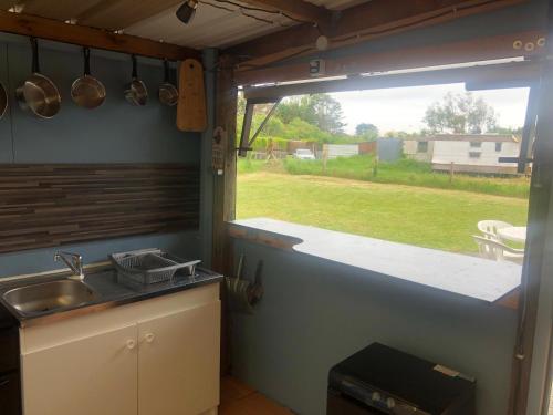 une cuisine avec un évier et une grande fenêtre dans l'établissement Mobil-home Atypique Manche SURVILLE -, à Surville