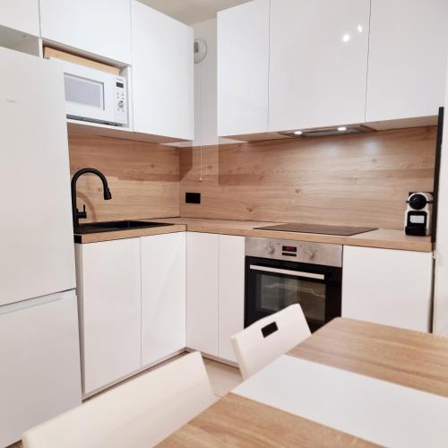 une cuisine avec des armoires blanches et un micro-ondes dans l'établissement T2 Paris Disneyland Jardin Parking, à Noisy-le-Grand