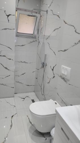 a white bathroom with a toilet and a sink at Luxury Room's by Lika in Sarandë