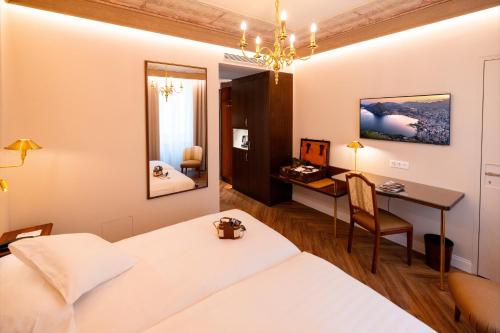 a hotel room with a bed and a desk and a table at International au Lac Historic Lakeside Hotel in Lugano