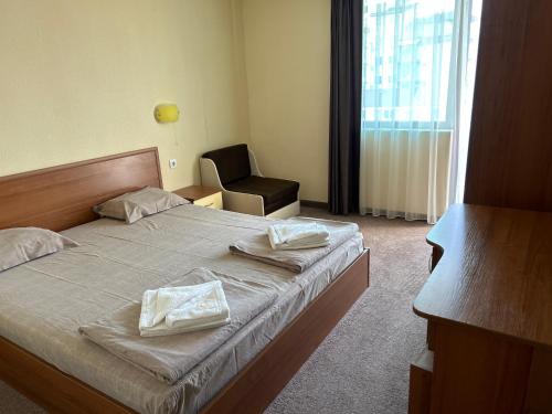 a bedroom with a bed with a chair and a window at Hotel SOLE in Primorsko