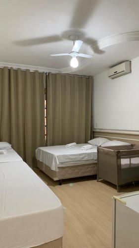 a room with two beds and a ceiling fan at Casa de Maria in Aparecida