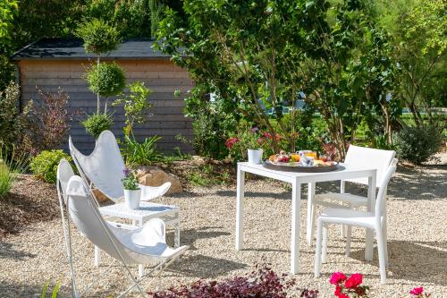 a white table and chairs in a garden at La Bastide de Damien, 5 clefs Demeure d'Exception et Table Remarquable dans le guide Teritoria, JACUZZI Privatif, Cuisine étoilée Dominique Frérard in Aix-en-Provence