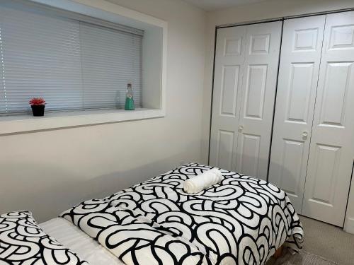 a bedroom with a black and white bed and a window at Private room in a Shared house in Vancouver