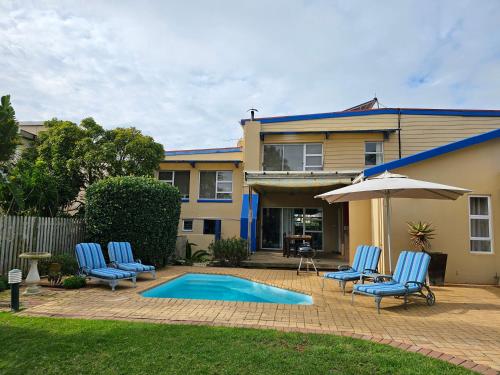a house with a swimming pool with chairs and an umbrella at 113 on Robberg in Plettenberg Bay