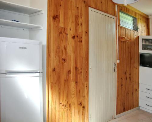 kuchnia z białą lodówką i drewnianą ścianą w obiekcie Appartement d'une chambre avec jardin clos et wifi a Port Louis w mieście Port-Louis
