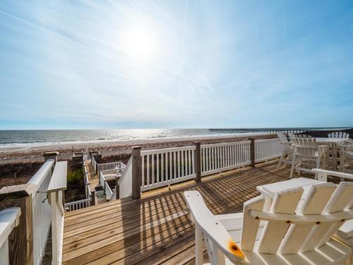a deck with white chairs and the beach at C-Maid in Surf City