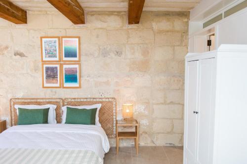 a bedroom with a bed with white sheets and green pillows at San Anton Suites in Attard