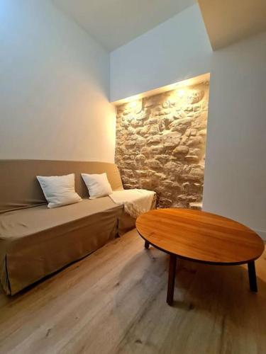 Cette chambre dispose d'un canapé, d'une table et d'un mur en pierre. dans l'établissement Spacieux 2 pièces, à Fontenay-aux-Roses