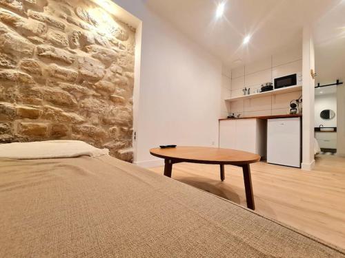 - une chambre avec une table et un mur en pierre dans l'établissement Spacieux 2 pièces, à Fontenay-aux-Roses