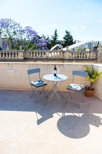 a table with two chairs and a bottle of wine at San Anton Suites in Attard