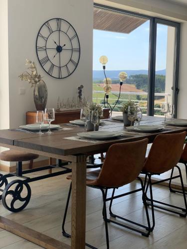 a wooden table with chairs and a large clock on the wall at Casa com Alma in Bombarral