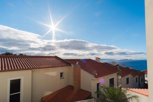 a sun shining in the sky over roofs at GuestReady - Paradise home in Caniço in Caniço