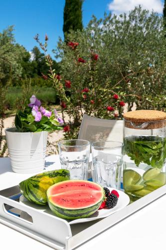 a table with a plate of watermelon and a bowl of fruit at La Bastide de Damien, 5 clefs Demeure d'Exception et Table Remarquable dans le guide Teritoria, JACUZZI Privatif, Cuisine étoilée Dominique Frérard in Aix-en-Provence