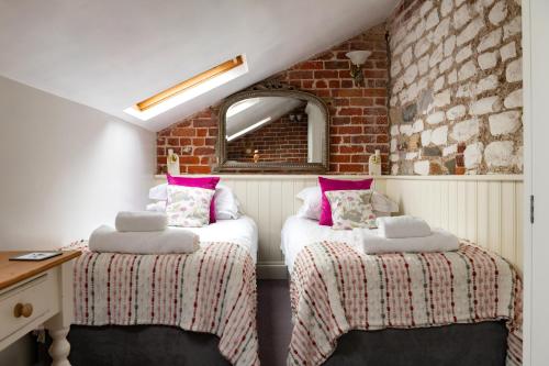 Dos camas en una habitación con una pared de ladrillo. en The Old Dairy, Heritage Escapes, Field House Farm, en Bempton