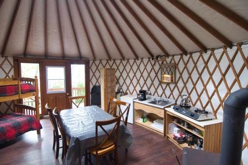 a room with a table and a kitchen in a yurt at Centre de Vacances 5 Étoiles Family Resort in Sacré-Coeur-Saguenay