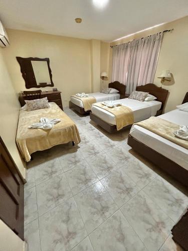 a hotel room with three beds and a mirror at Hotel Madrid Chiriqui in David