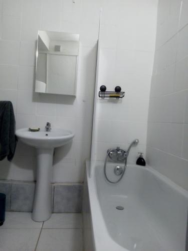 La salle de bains blanche est pourvue d'un lavabo, d'une baignoire et d'un lavabo. dans l'établissement Au cœur de Narbonne, à Narbonne