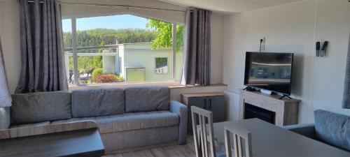 a living room with a couch and a large window at Camping Panorama in Bourscheid