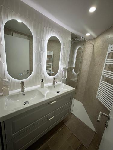 une salle de bain blanche avec un lavabo et un miroir dans l'établissement Centre Ville & Plage à 200m - Clim - Parking Privé - Netflix, au Grau-du-Roi