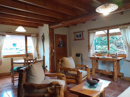 a living room with chairs and a table and windows at Tierras del Sur II in Villa La Angostura