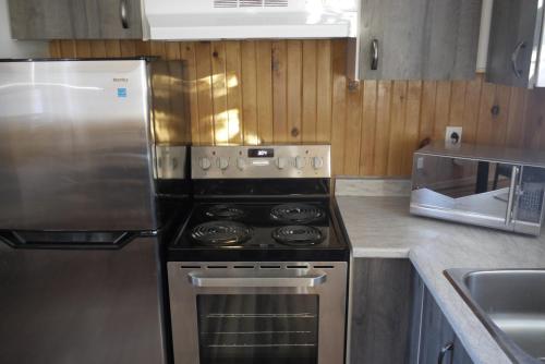 a kitchen with a stove and a stainless steel refrigerator at Centre de Vacances 5 Étoiles Family Resort in Sacré-Coeur-Saguenay