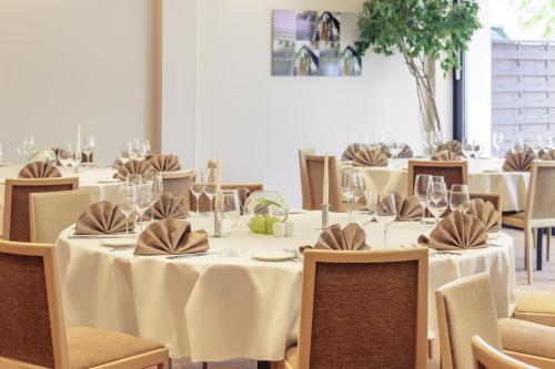 a dining room with tables and chairs with wine glasses at Mercure Hotel Frankfurt Eschborn Ost in Eschborn
