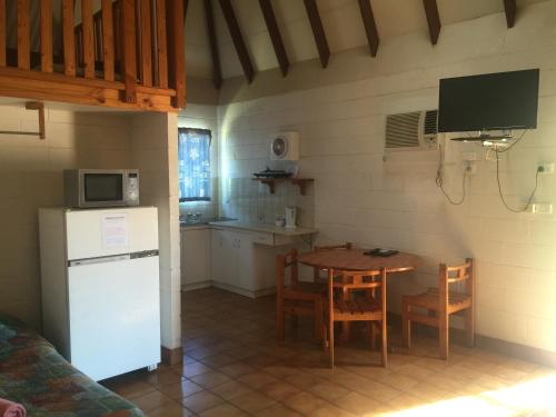 una piccola cucina con tavolo e frigorifero bianco di Carnarvon Caravan Park a Carnarvon