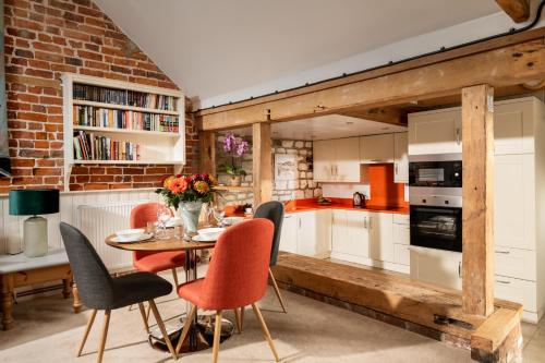 cocina con mesa, sillas y pared de ladrillo en The Old Dairy, Heritage Escapes, Field House Farm, en Bempton