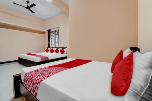 um quarto com 2 camas com almofadas vermelhas e brancas em OYO Dhanam Lodge em Coimbatore