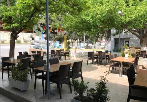 an outdoor restaurant with tables and chairs and trees at Kılıç AirPort otel in Seydiköy