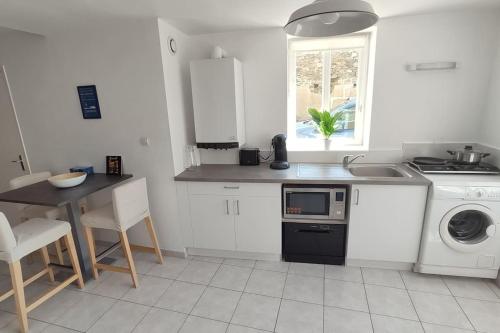 une cuisine avec une table, un évier et une cuisinière dans l'établissement Roscoff 2 pièces classé 2 étoiles et terrasse centre historique, à Roscoff