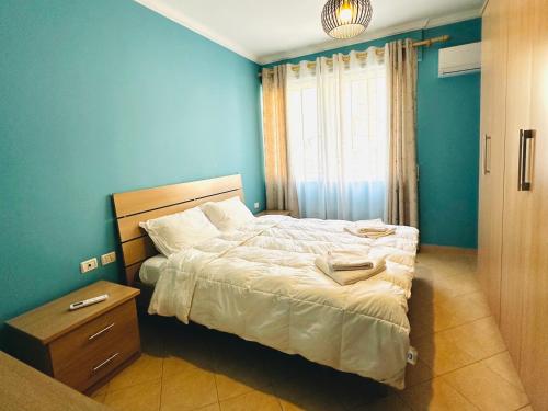 een slaapkamer met een bed en een blauwe muur bij Quiet & spacious city center apartment - 4 min walk in Tirana