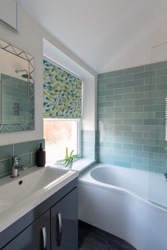 a bathroom with a tub and a sink and a window at King's Head Cottage in Hastings