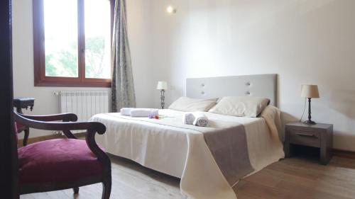 a bedroom with a white bed with a chair and a window at Capalbio - Retreat in Capalbio