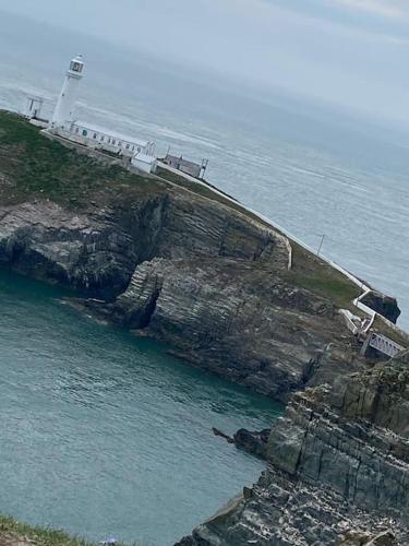 a lighthouse on a cliff next to the ocean at Seabird at Trearddur Bay in Trearddur