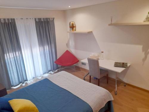a bedroom with a bed and a desk with a red chair at Quartos com casa de banho privada perto da Malveira in Asseiceira Grande