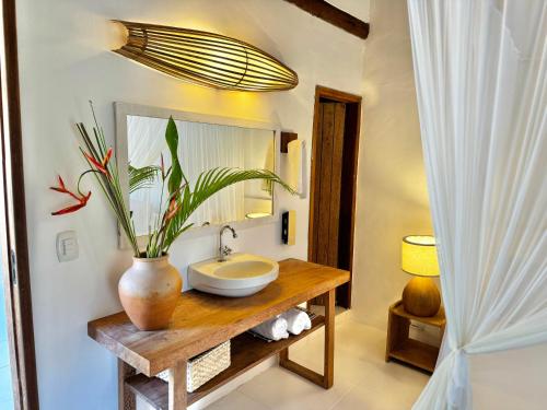 a bathroom with a sink and a vase with a plant at Casa Rabanete Trancoso in Trancoso