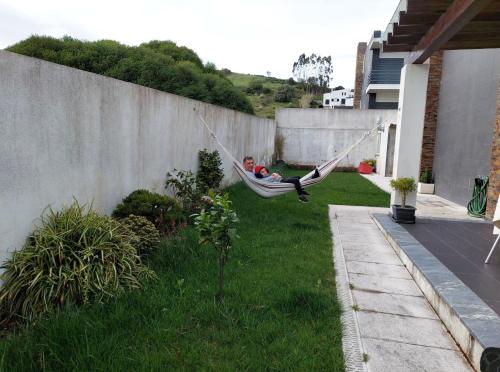 a man sitting in a hammock in a yard at Quartos com casa de banho privada perto da Malveira in Asseiceira Grande