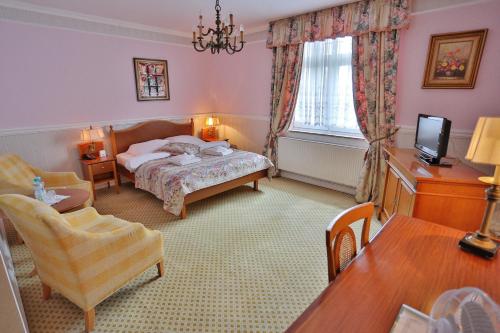 a bedroom with a bed and a tv and a table at Hotel Garden in Bolesławiec
