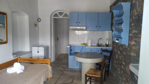 a small kitchen with blue cabinets and a table at Stone Oasis apartment Vari Syros in Vari