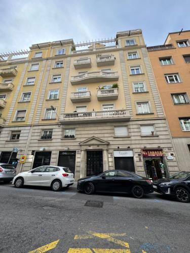 Dos coches aparcados delante de un gran edificio. en Pensión Laforja, en Barcelona
