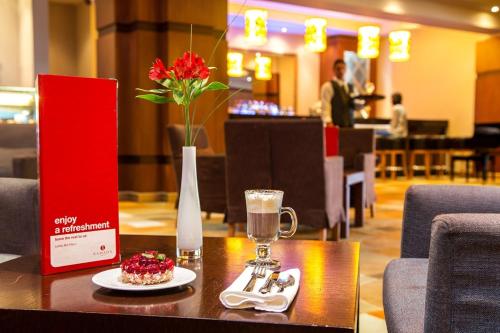 a table with a vase of flowers and a plate of food at Ramada by Wyndham Sofia City Center in Sofia