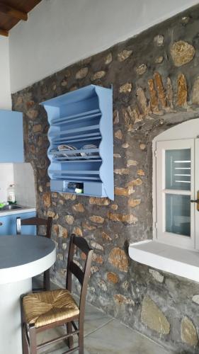 a kitchen with a stone wall with a table and chairs at Stone Oasis apartment Vari Syros in Vari